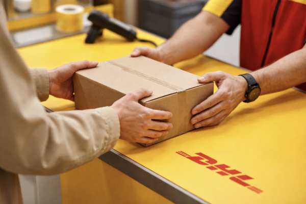 Eine Person übergibt einer anderen Person ein Paket an einem Postschalter
